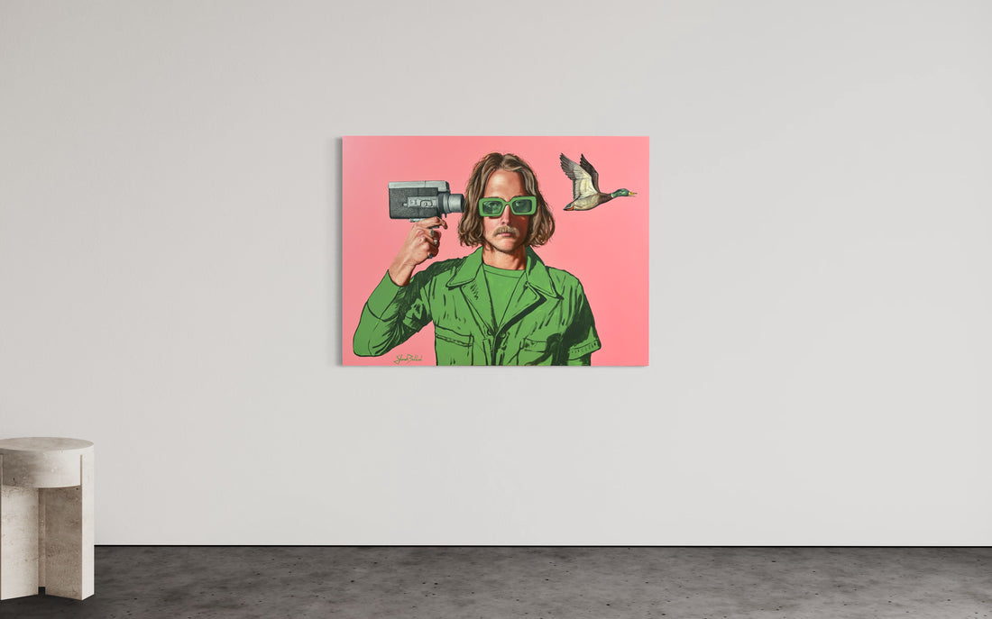 A canvas print featuring a colorful illustration of a person with sunglasses and a camera, positioned against a pink background, displayed on a white wall.