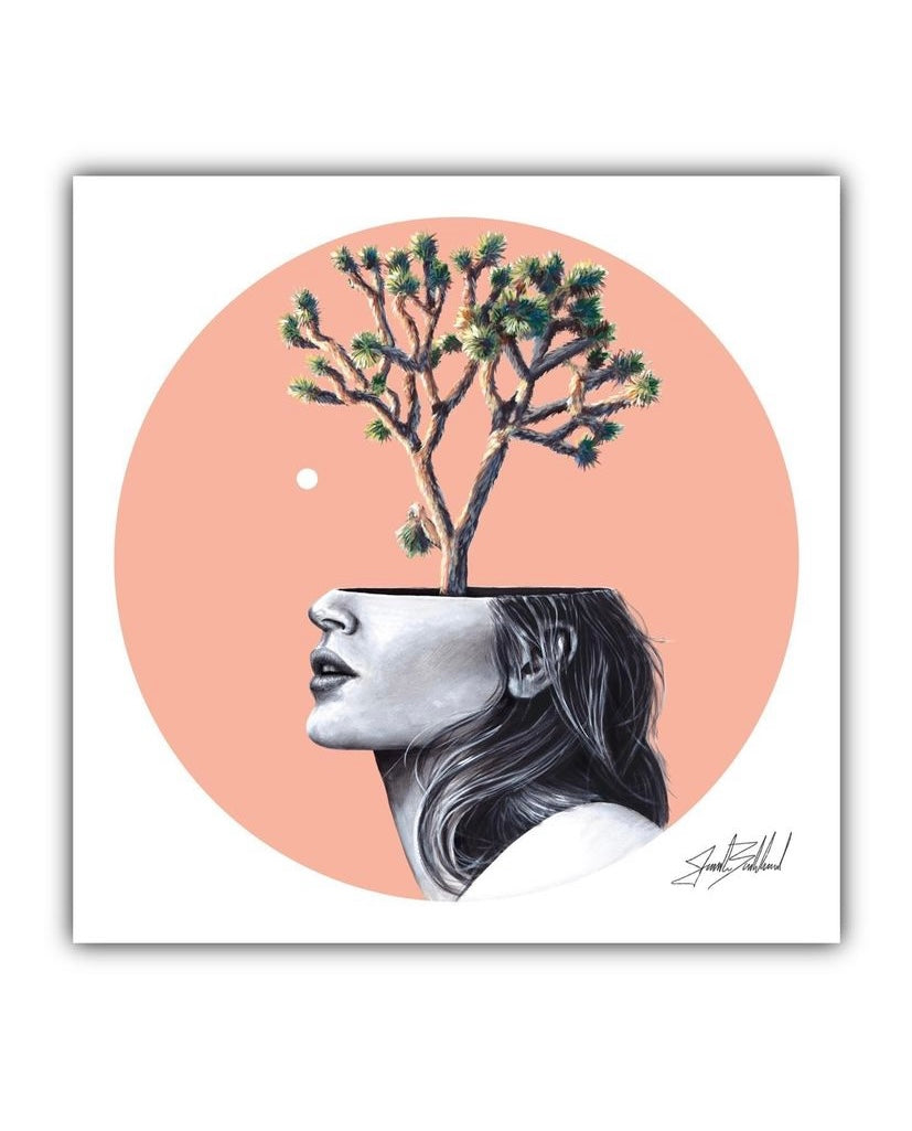 Artistic paper print depicting a stylized female head silhouette with a tree growing in place of the head, set against a pink circular background.