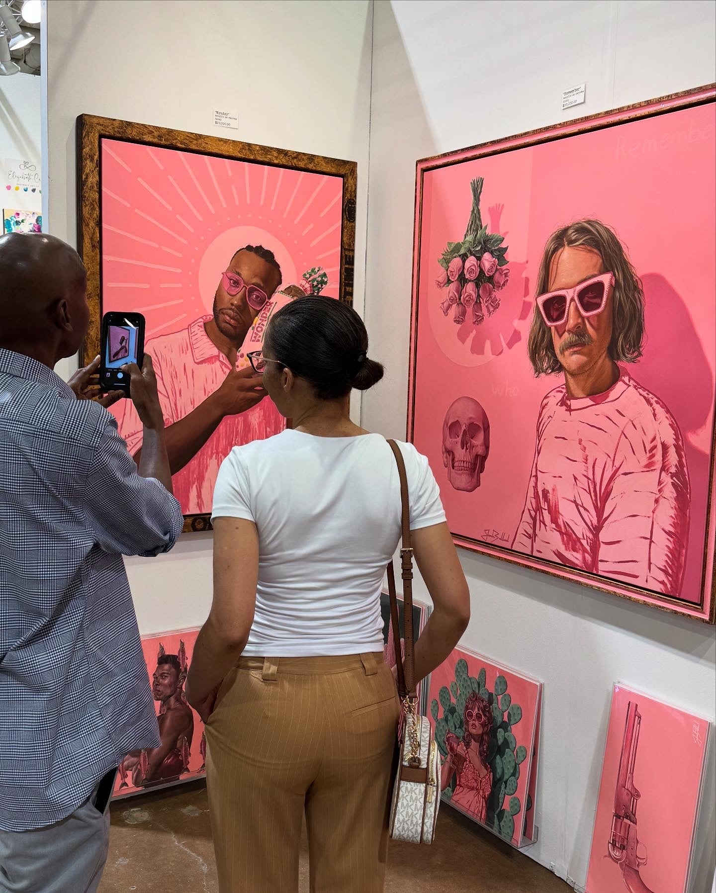 Two people looking at artwork in a gallery with pink tones.
