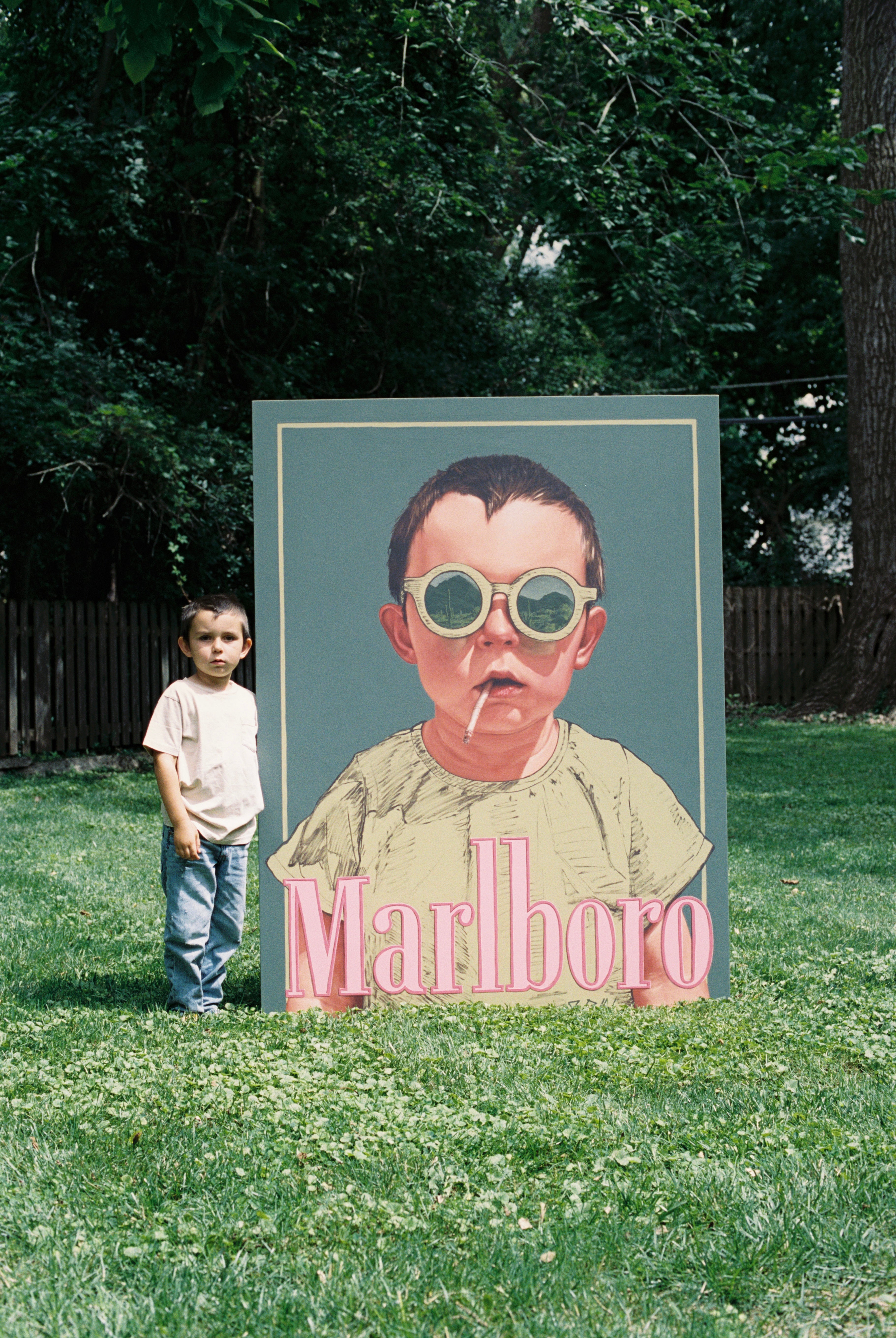 Child standing next to a large ready to hang canvas painting by Jonah Ballard
